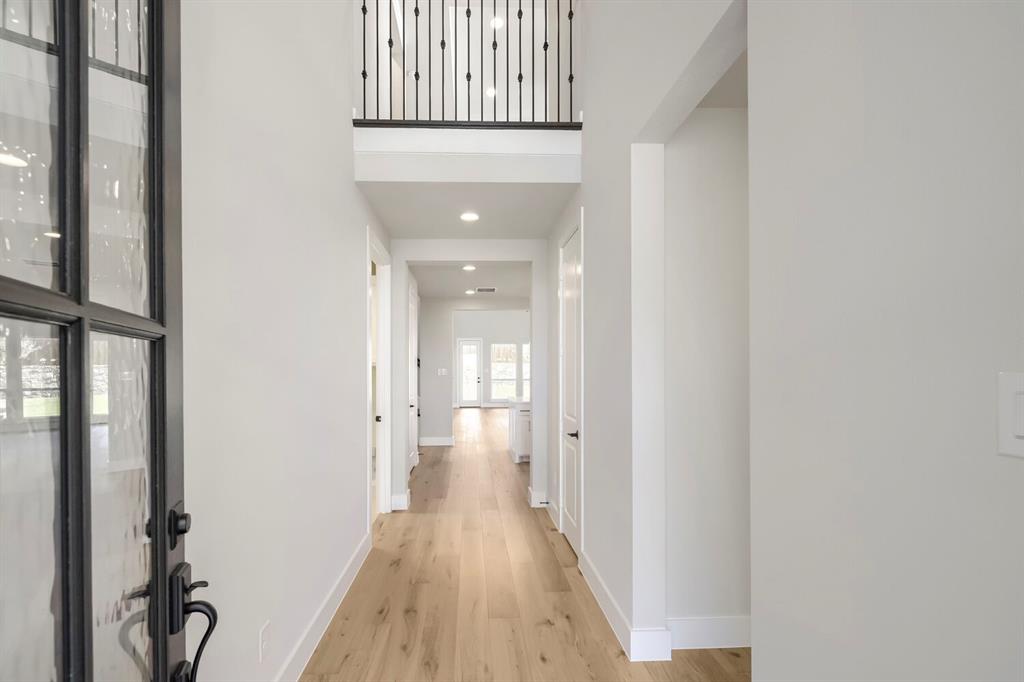 800 Blackberry Road Haslet, TX 76052 - Photo 2 of 28 Foyer featuring a two-story ceiling, wood-finish flooring, a contemporary iron and glass entry door, recessed lighting, and a second-story overlook with an iron balustrade