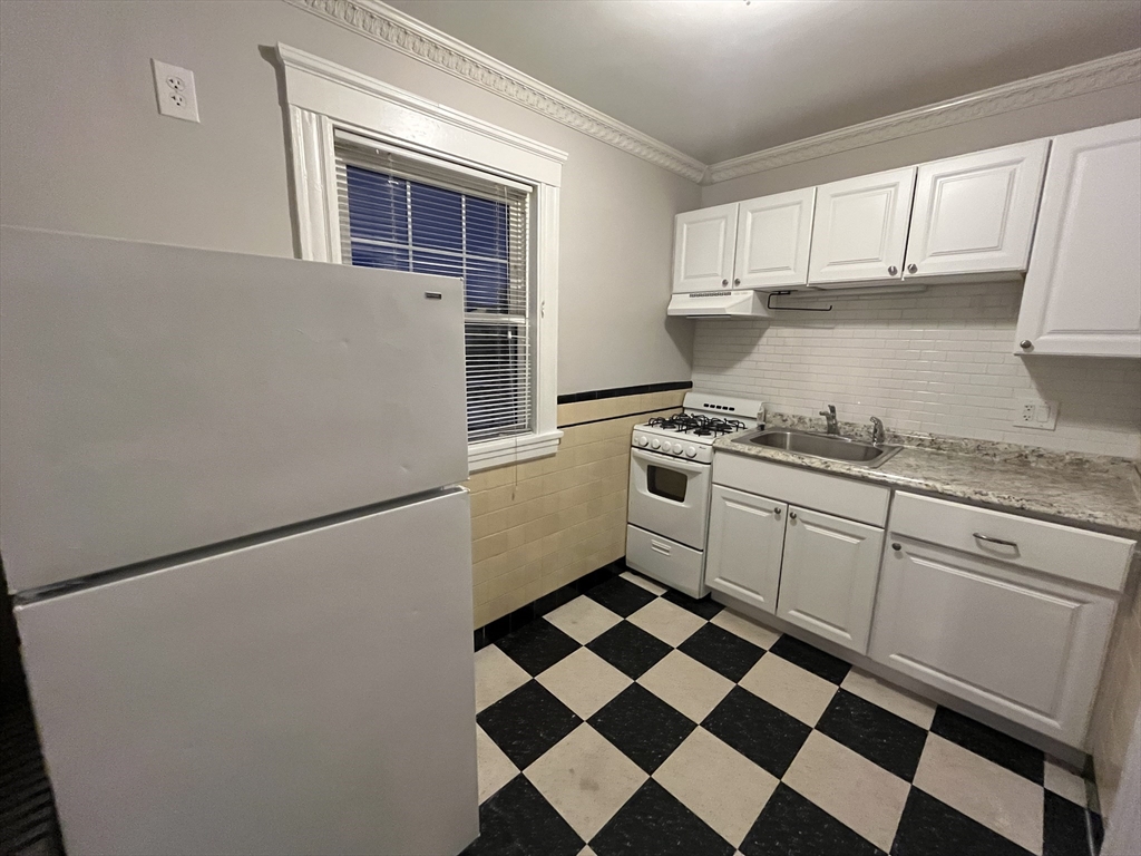 a kitchen with a checkered floor and white cabinets