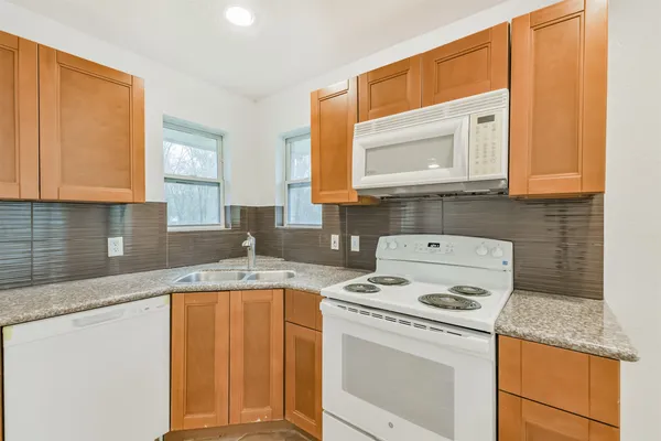 a kitchen with granite countertop a sink stove and cabinets