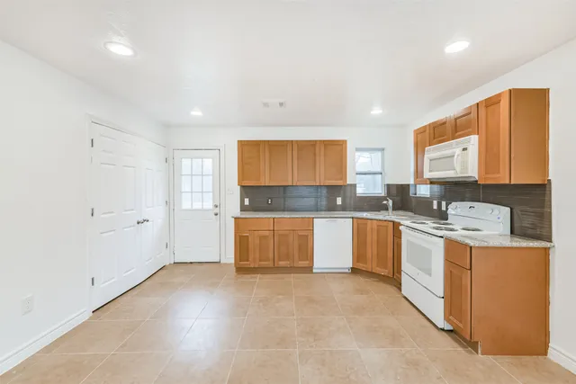 a large kitchen with stainless steel appliances granite countertop a stove a sink and a refrigerator
