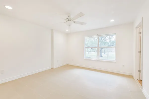 an empty room with a window and a fan