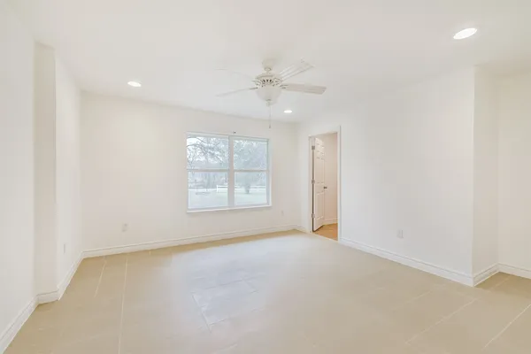 an empty room with a ceiling fan and window