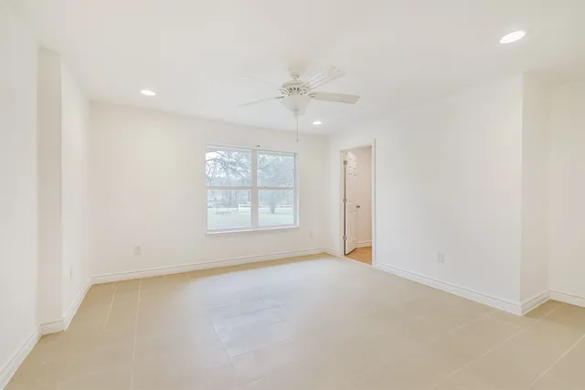 an empty room with a ceiling fan and window