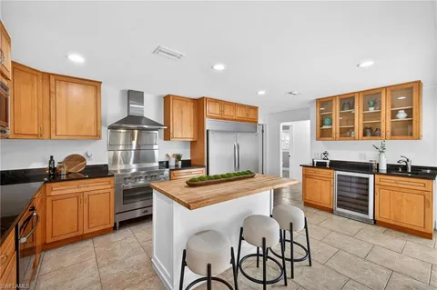 a kitchen with stainless steel appliances granite countertop wooden cabinets a stove a sink a dining table and chairs
