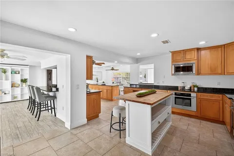 a kitchen with stainless steel appliances granite countertop a kitchen island a table and chairs in it