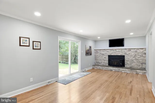 a view of a livingroom with a fireplace a ceiling fan and windows
