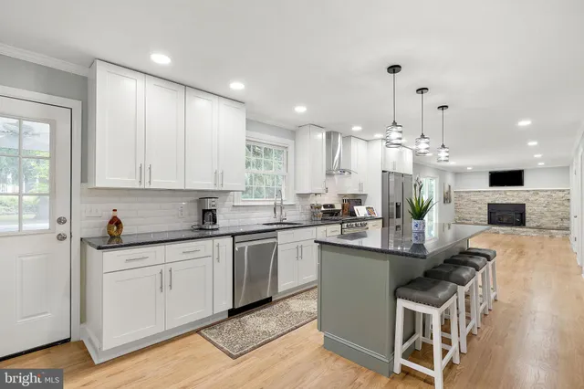 a kitchen with kitchen island granite countertop a sink and white cabinets