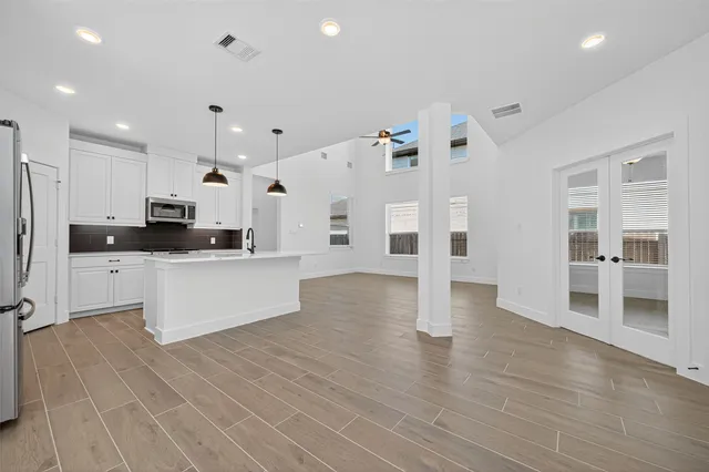 a large kitchen with stainless steel appliances a large counter top and wooden floors