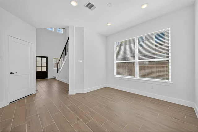 a view of an empty room with a window and wooden floor