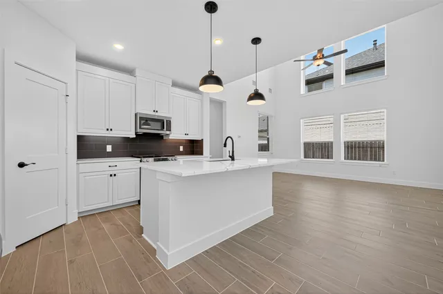 a large kitchen with granite countertop a stove a sink a center island and wooden floor