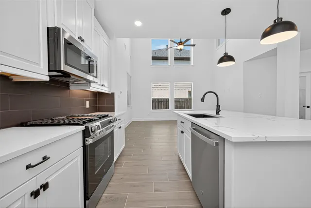 a kitchen with stainless steel appliances granite countertop a sink a stove and a wooden floors