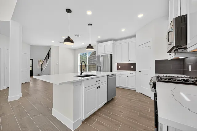 a large kitchen with kitchen island a sink a counter space and stainless steel appliances
