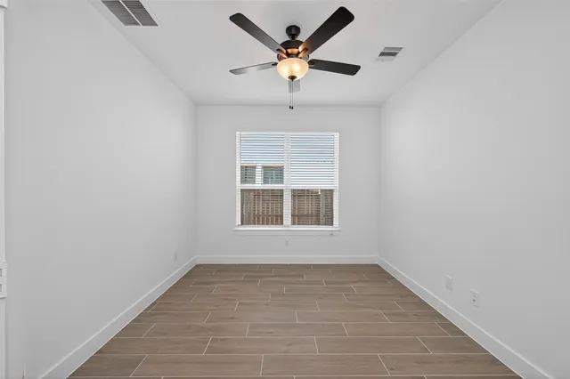 an empty room with wooden floor and ceiling fan