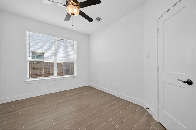 a view of empty room with wooden floor and fan