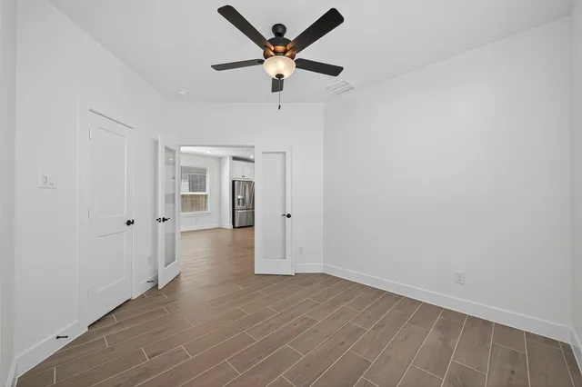 an empty room with wooden floor and a ceiling fan