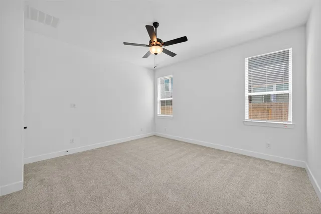 an empty room with windows and fan