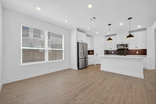 a large kitchen with stainless steel appliances granite countertop a large counter top a refrigerator and a sink