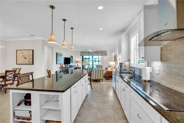 a kitchen with stainless steel appliances granite countertop a sink a counter top space and living room view