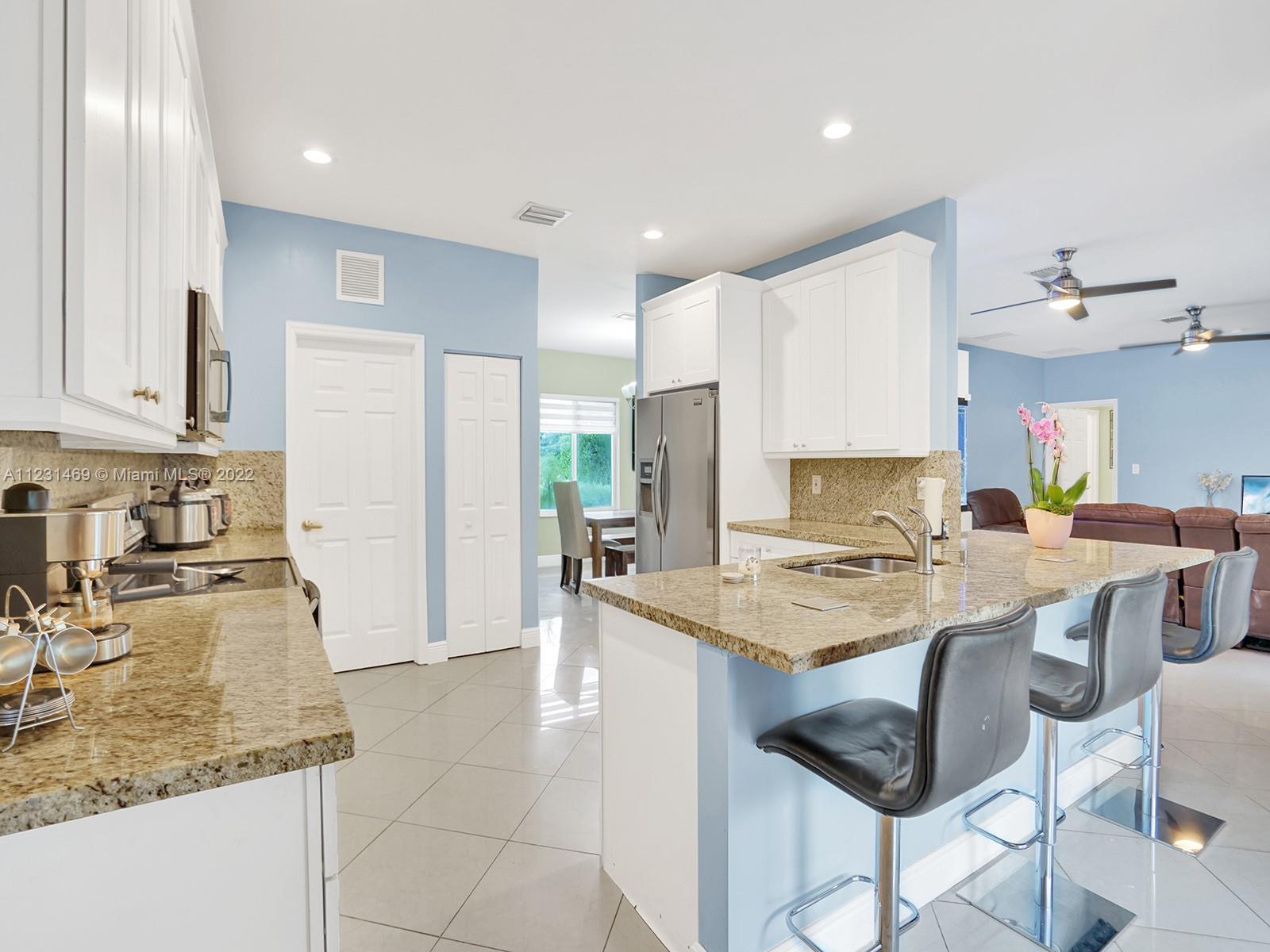 17335 Southwest 298th Street Homestead, FL 33030 - Photo 13 of 32 a kitchen with stainless steel appliances granite countertop a sink refrigerator and cabinets
