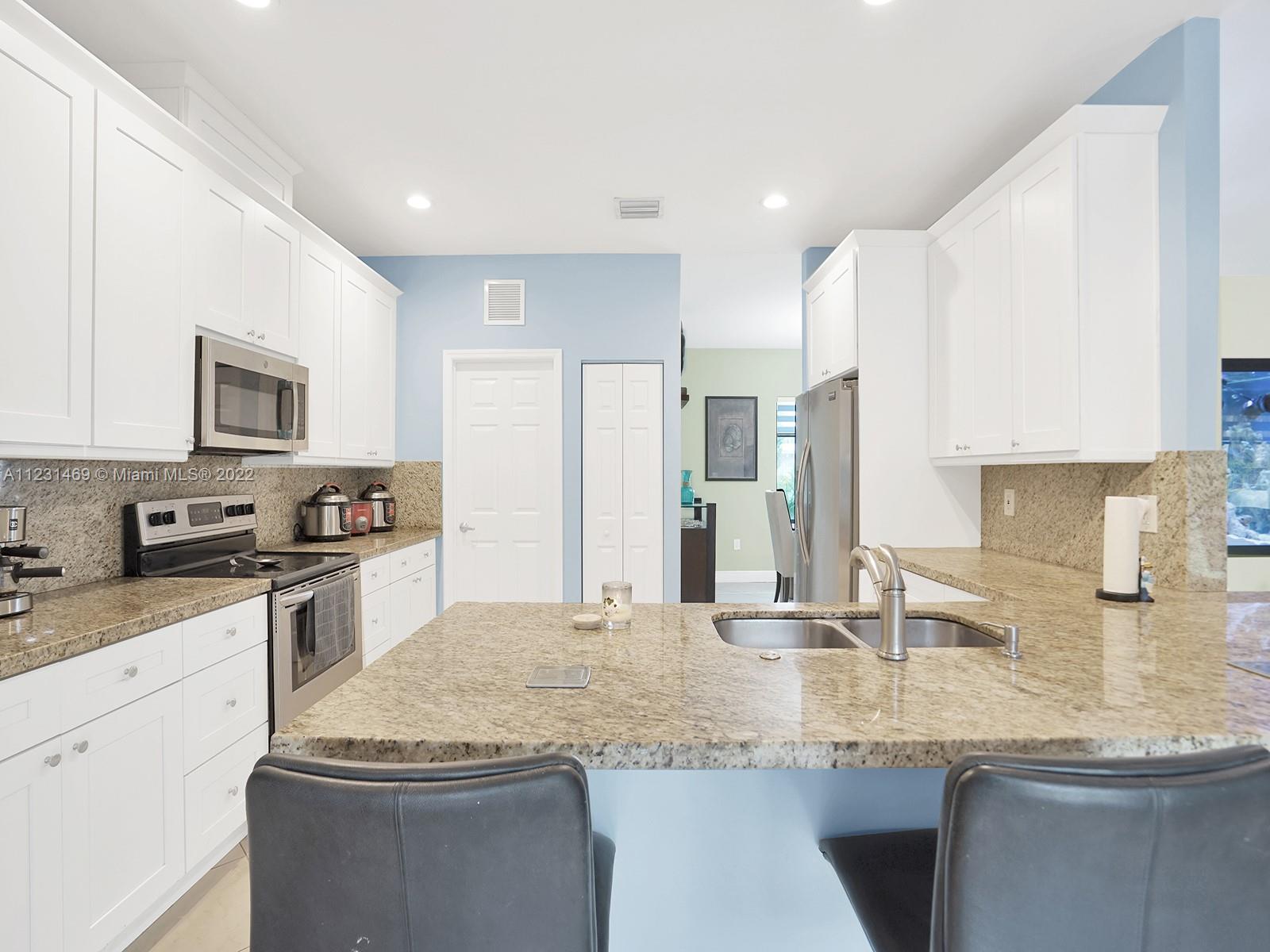 17335 Southwest 298th Street Homestead, FL 33030 - Photo 14 of 32 a kitchen with granite countertop a sink stainless steel appliances and white cabinets