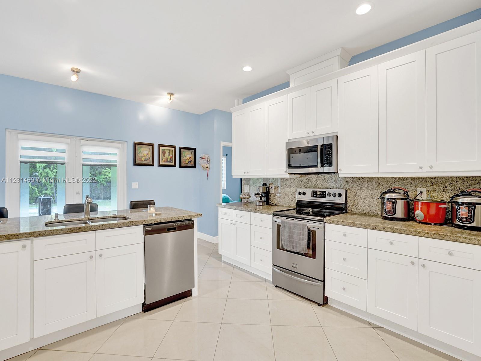 17335 Southwest 298th Street Homestead, FL 33030 - Photo 15 of 32 a kitchen with granite countertop white cabinets and white appliances