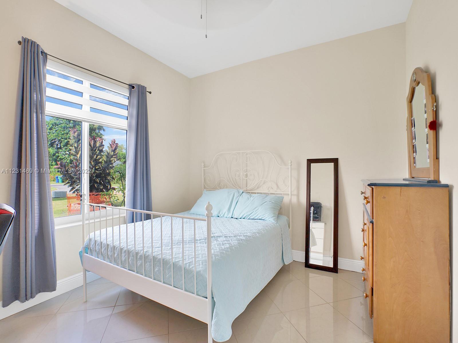 17335 Southwest 298th Street Homestead, FL 33030 - Photo 17 of 32 a bedroom with a bed and a large window