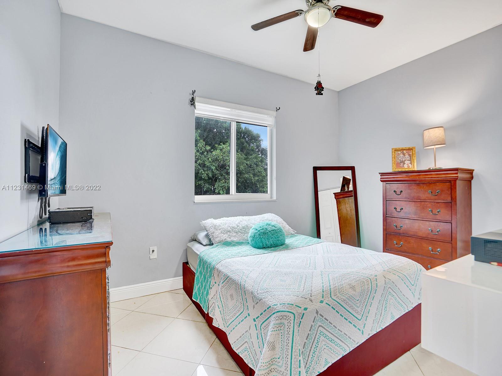 17335 Southwest 298th Street Homestead, FL 33030 - Photo 25 of 32 a bedroom with a bed dresser and a flat tv screen