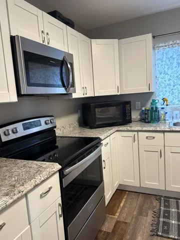 a kitchen with granite countertop white cabinets and white appliances