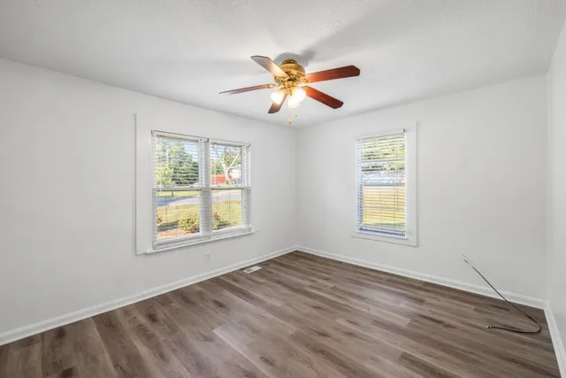 a view of an empty room with window and wooden floor