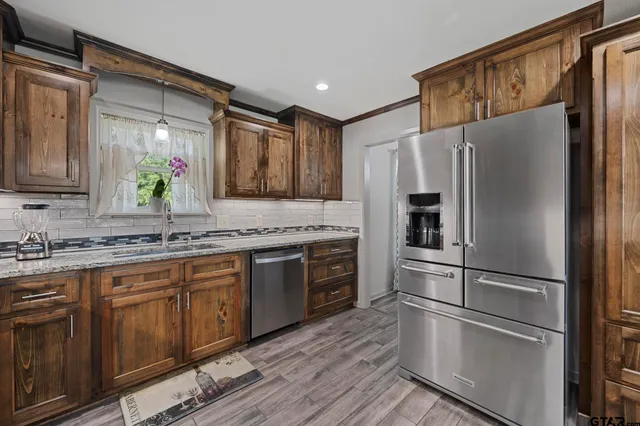 a kitchen with granite countertop stainless steel appliances a refrigerator sink and microwave