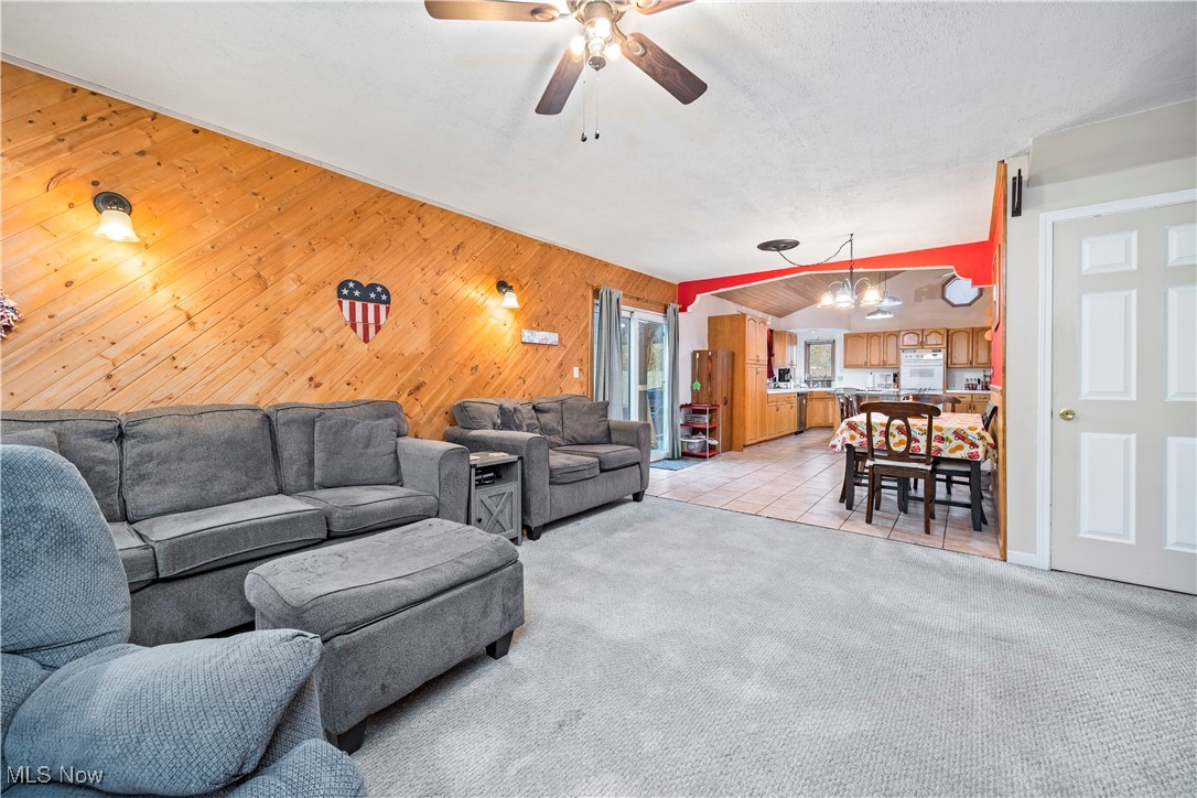 5569 Lear Nagle Road North Ridgeville, OH 44039 - Photo 17 of 41 Tiled living room featuring a textured ceiling, ceiling fan with notable chandelier, and wooden walls