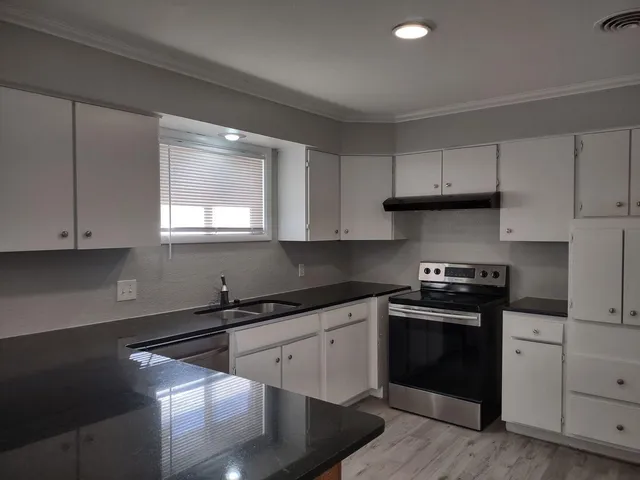 a kitchen with cabinets appliances a sink and a window