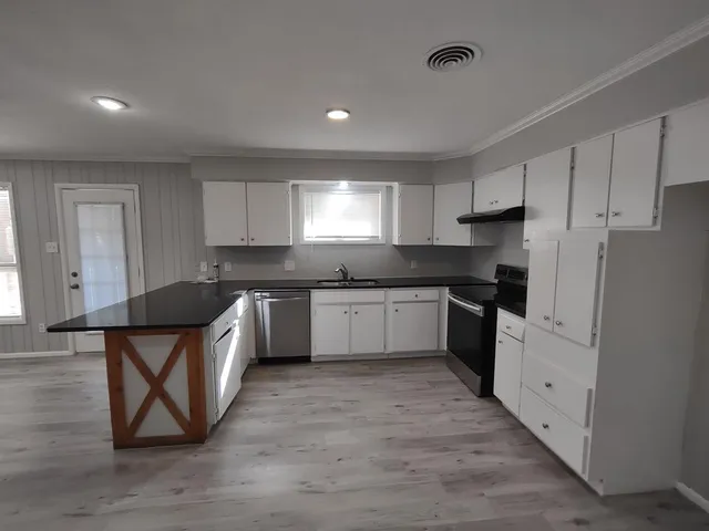 a kitchen with granite countertop a sink cabinets and stainless steel appliances