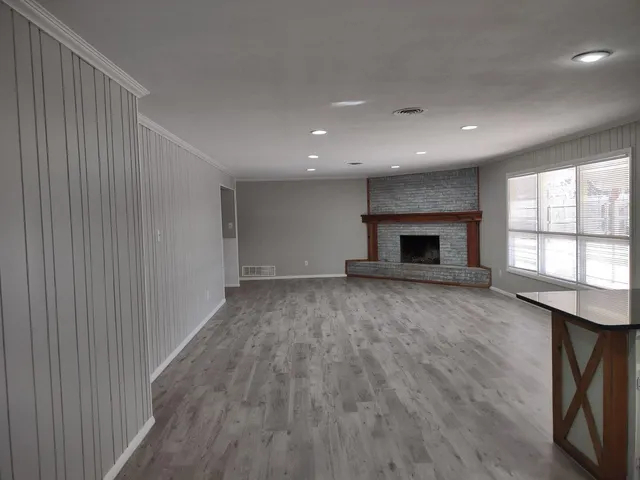 an empty room with wooden floor fireplace and windows