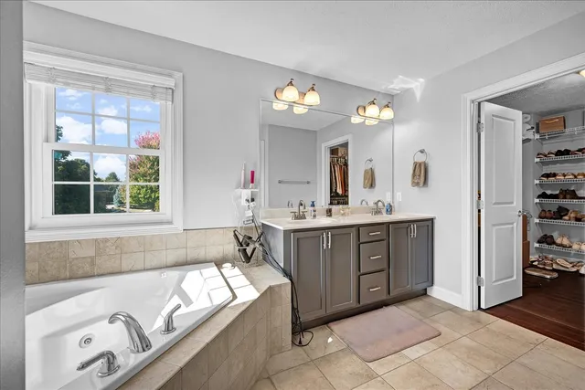 a spacious bathroom with a tub sink and mirror