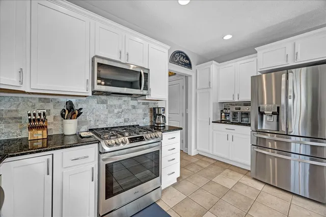 a kitchen with granite countertop a refrigerator stove and microwave