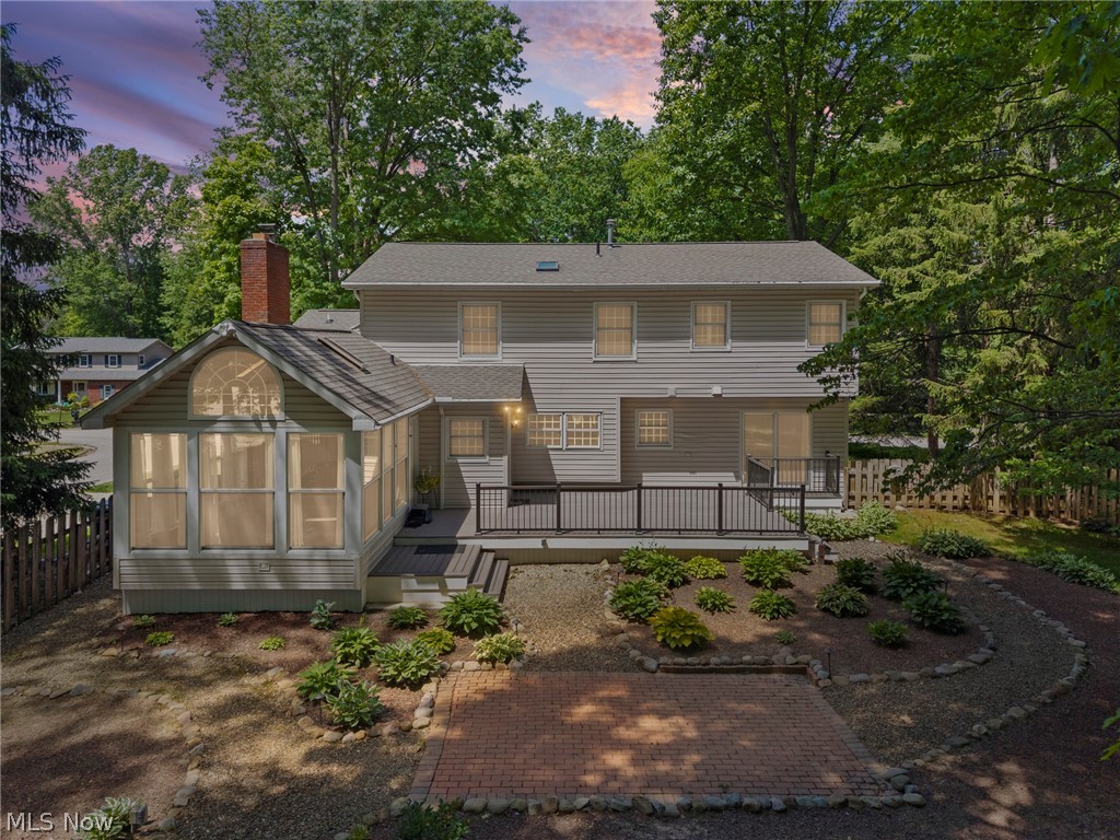 3871 Greentree Road Stow, OH 44224 - Photo 41 of 50 Gray siding exterior featuring a multi-level deck, a sunroom with an arched transom window, a brick chimney, and a lower paver patio