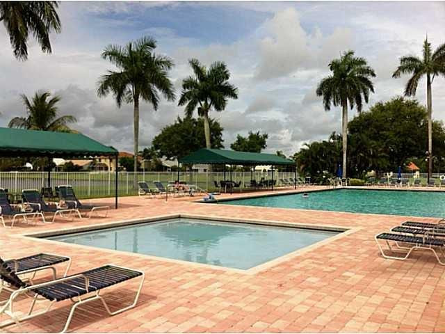 18897 Cloud Lake Circle Boca Raton, FL 33496 - Photo 22 of 23 a view of a swimming pool with a lawn chairs under palm trees