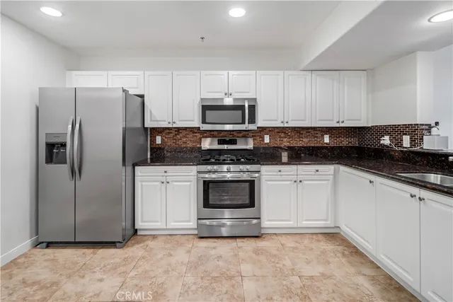 a kitchen with granite countertop white cabinets and sink