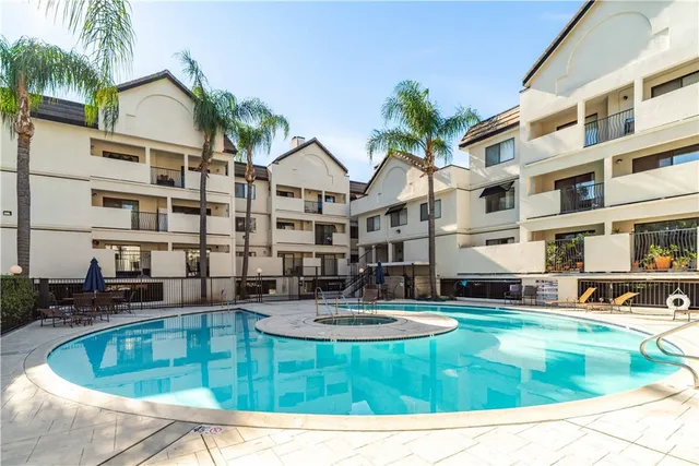a front view of a building with glass windows and plants