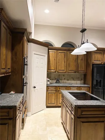 a kitchen with granite countertop a sink a counter space and stainless steel appliances