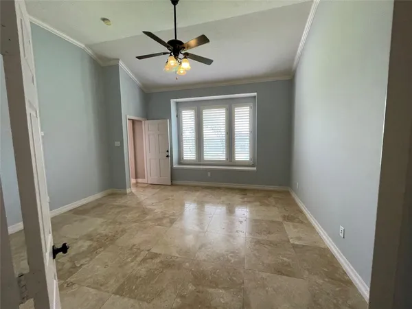 an empty room with chandelier fan and windows
