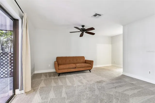 an empty room with wooden floor ceiling fan and window