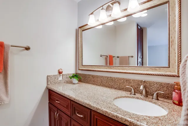 a bathroom with a granite countertop sink and a mirror