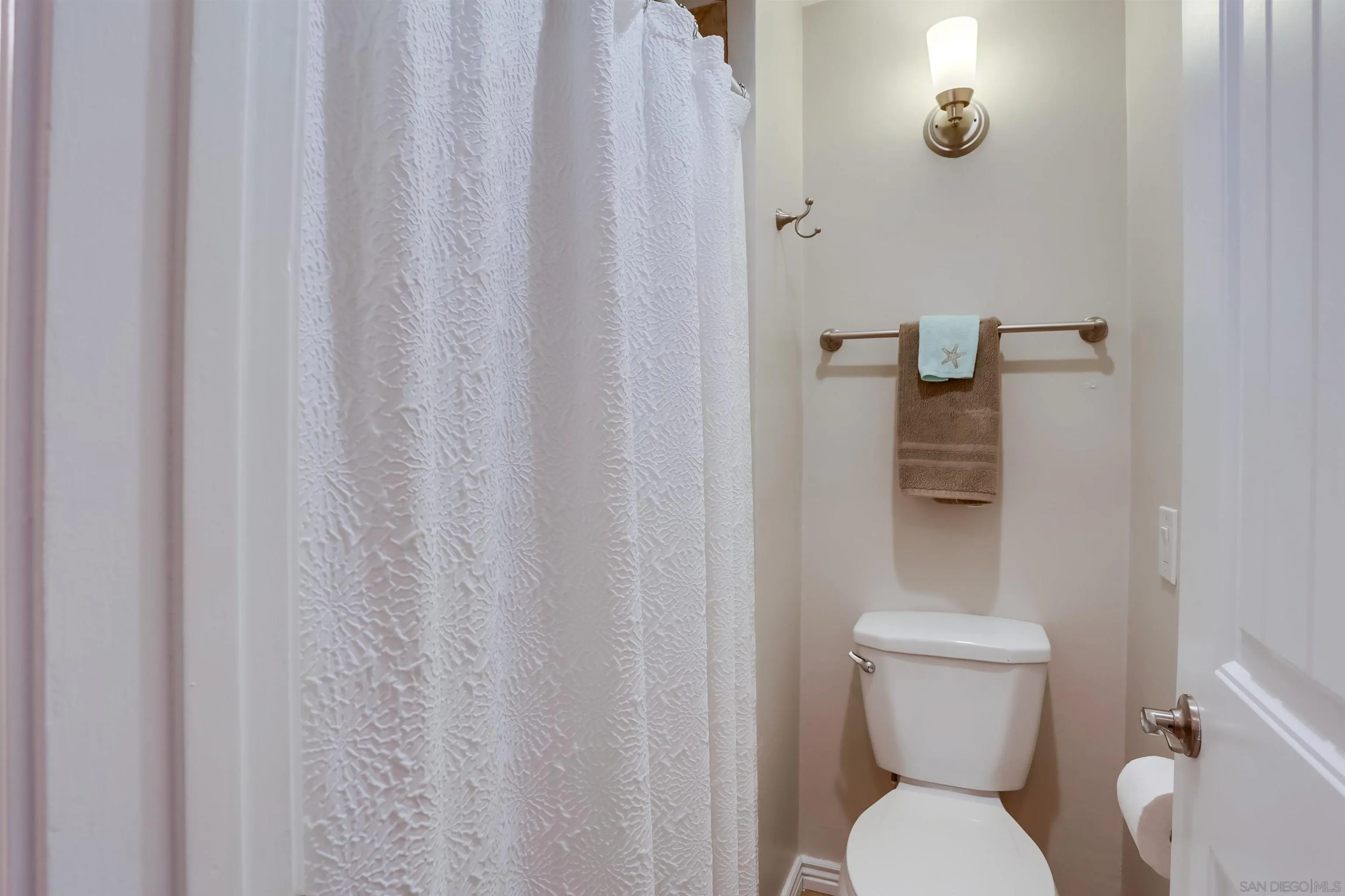 1775 Diamond Street, Unit 220 San Diego, CA 92109 - Photo 15 of 21 a white toilet sitting next to a shower curtain
