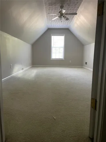 an empty room with a chandelier fan and windows
