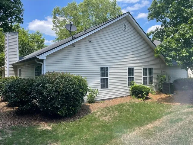 a view of a house with a yard plants and a large tree