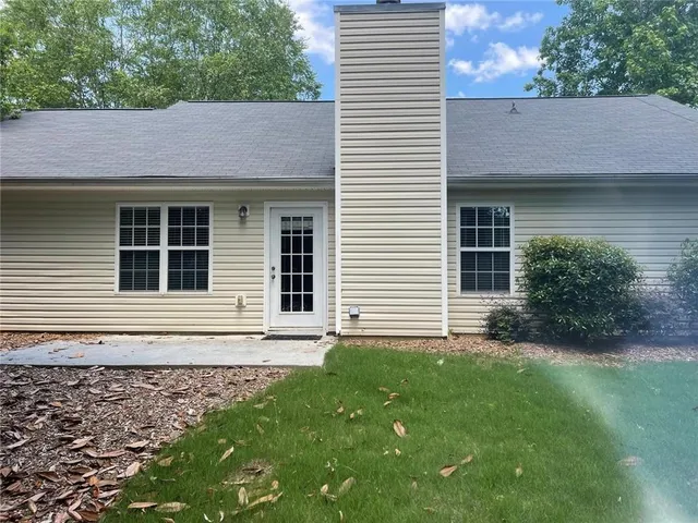 a view of a house with a yard and a large tree