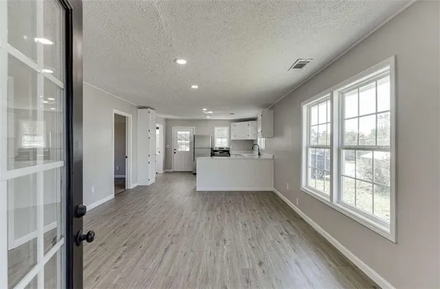 an empty room with wooden floor and windows