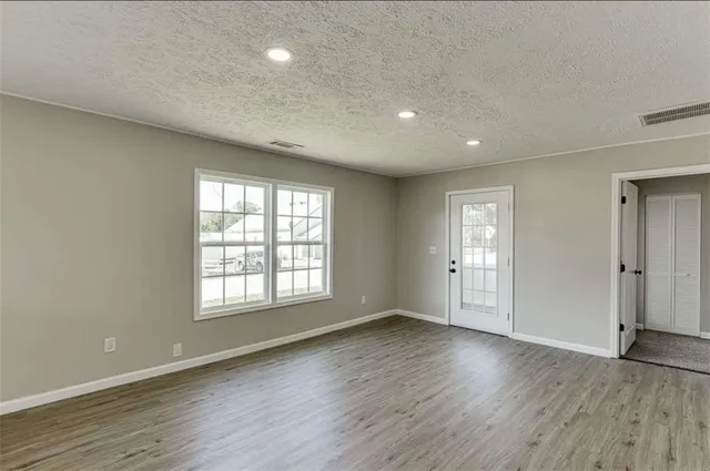a view of an empty room with a window and wooden floor